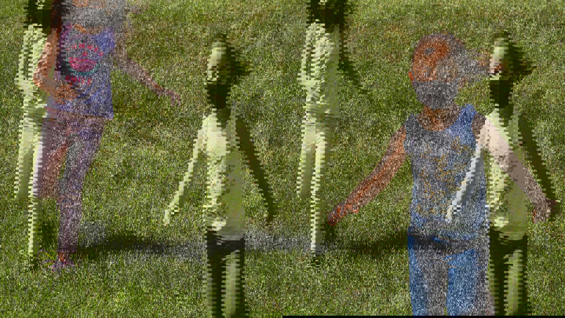 girl in white shirt and blue denim jeans standing on green grass field during daytime