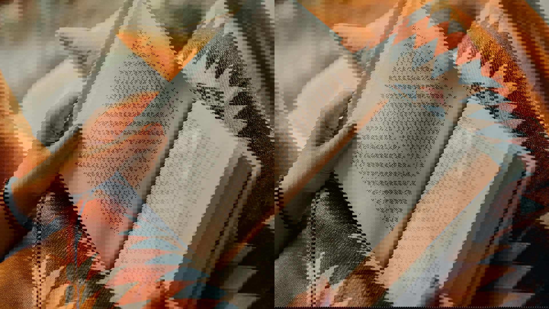 person reading book on brown and beige textile